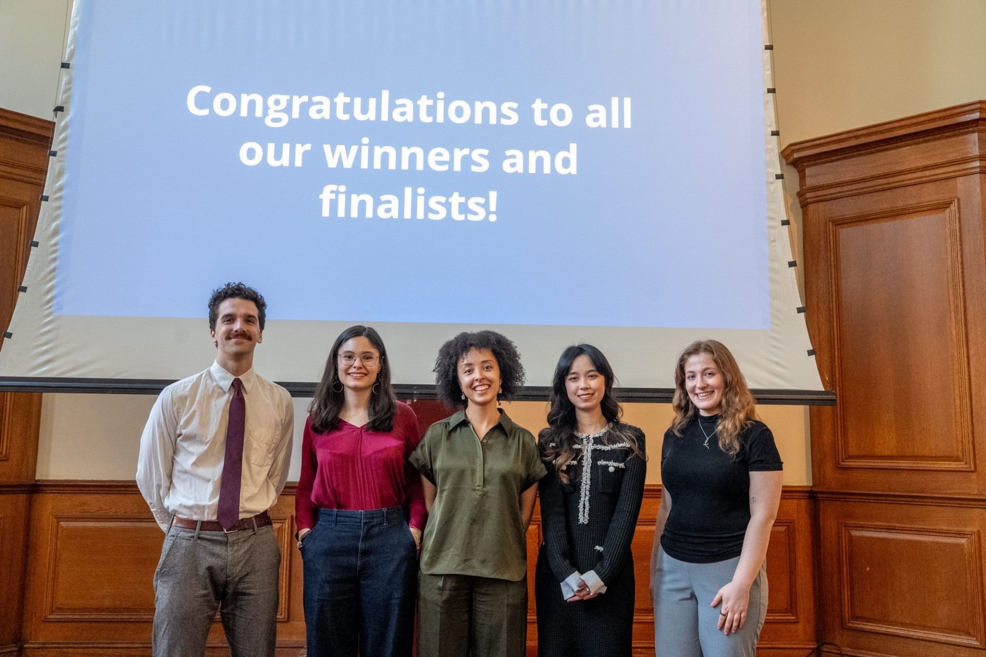 Winners (L to R): Peter Silverstein (Quantitative Methods in the Social Sciences), Teresa Mondría Terol (Quantitative Methods in the Social Sciences), Kimberly Snijders (Global Thought), Siyu Hua (Sociology), Dani Pergola (Ecology, Evolution and Conservation Biology). Five students smile beneath a projector screen that reads "Congratulations to all our winners and finalists!"