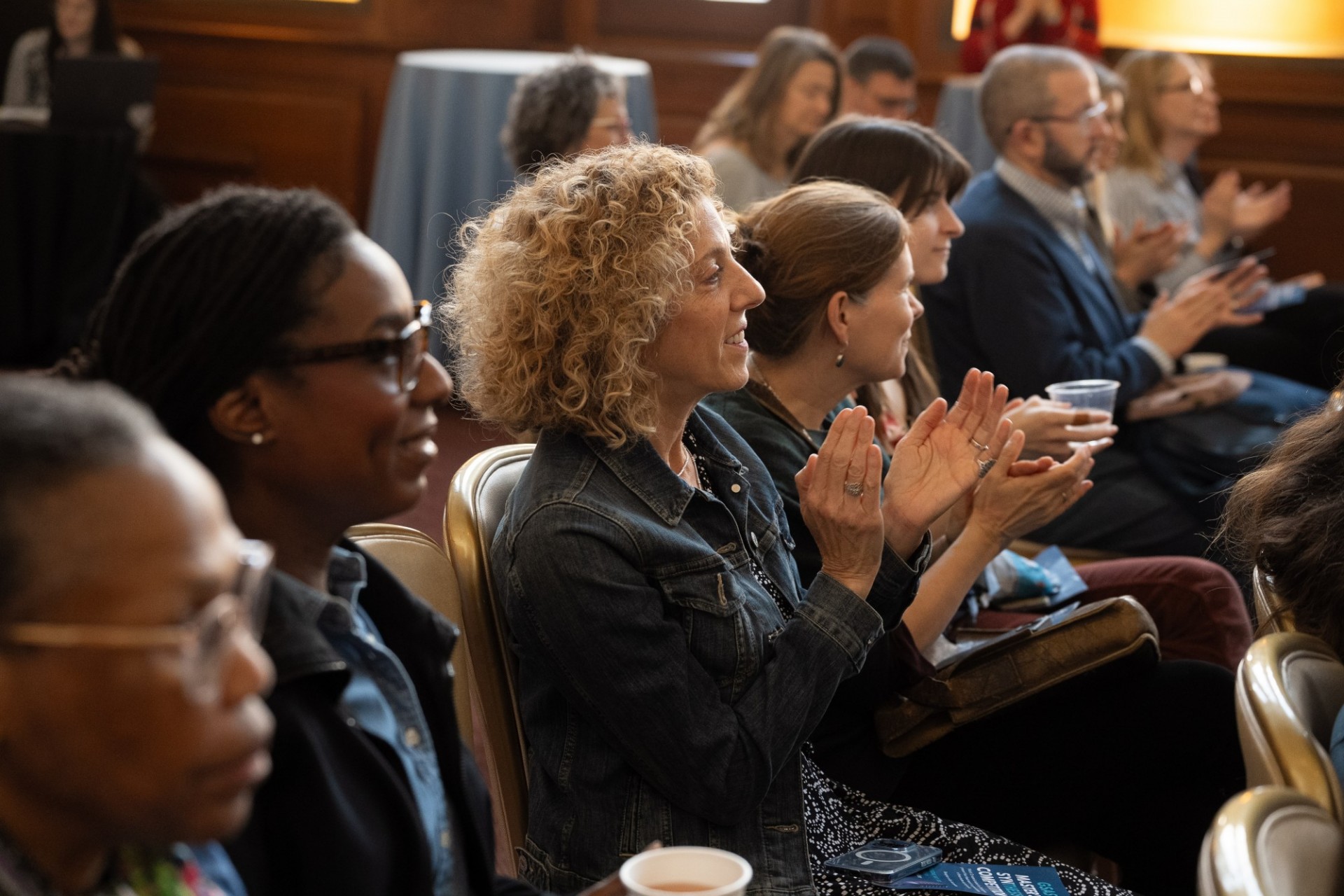Gennet Black, Senior Assistant Dean of Academic Programs, and Vice Dean Andrea Solomon (clapping) watch the presentations. Audience members clapping.