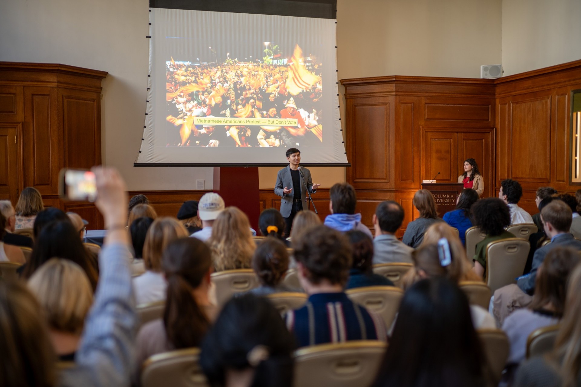Haakon Huynh (Global Thought) presenting "Why Vietnamese Diasporas Protest—But Often Don’t Vote." A man speaking and standing in front of a slide that shows a crowd of people.