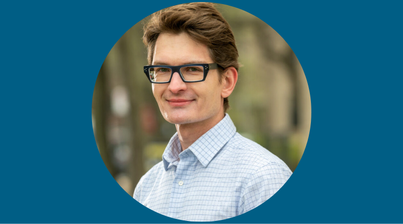 A portrait of a man in a button-up shirt wearing glasses.