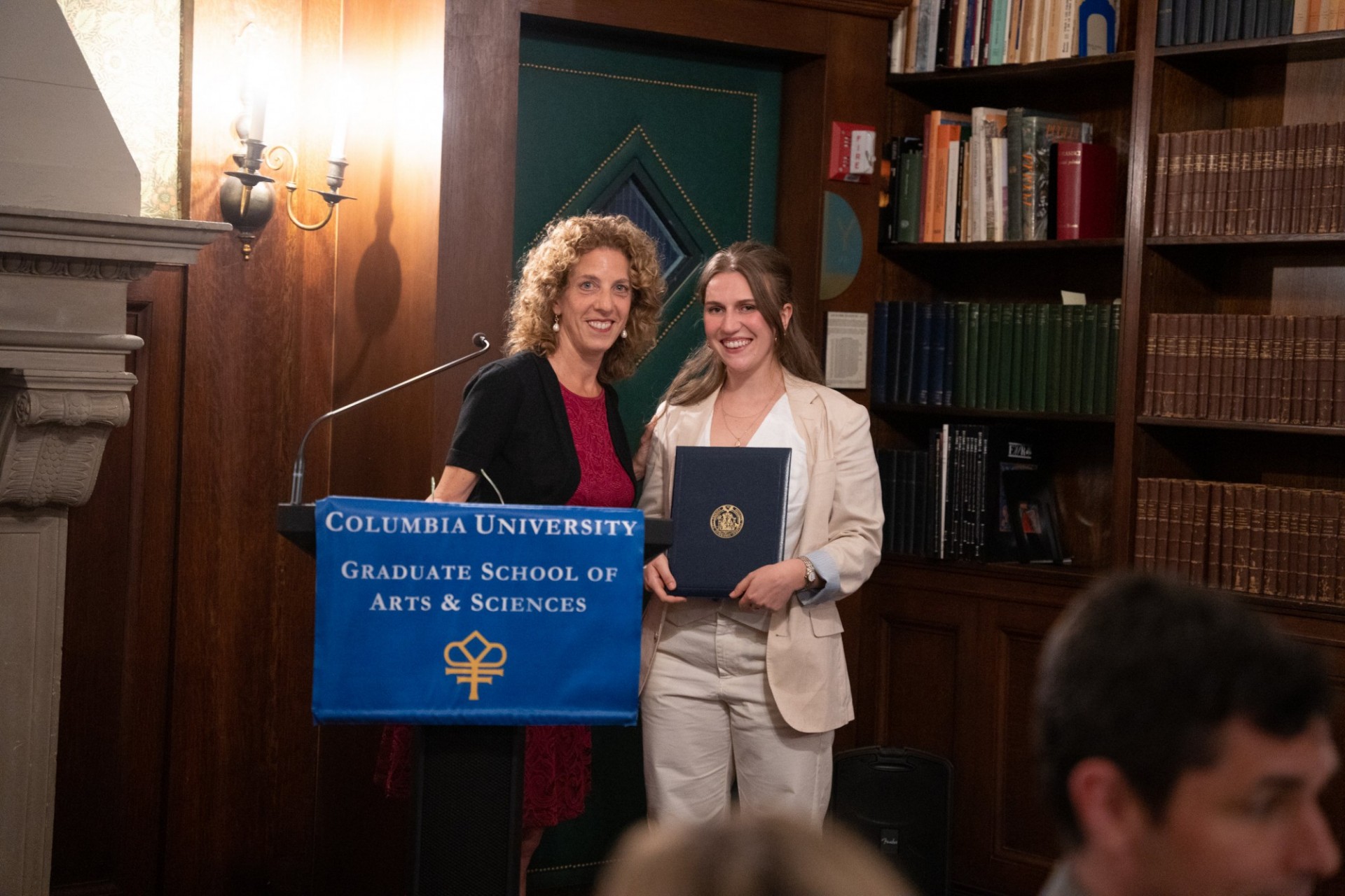 Vice Dean Andrea Solomon with Ana DiGiovanna (’23MPhil, Psychology) recipient of The Presidential Award for Outstanding Teaching by a Graduate Student Two women at lectern, facing camera, one holding an award