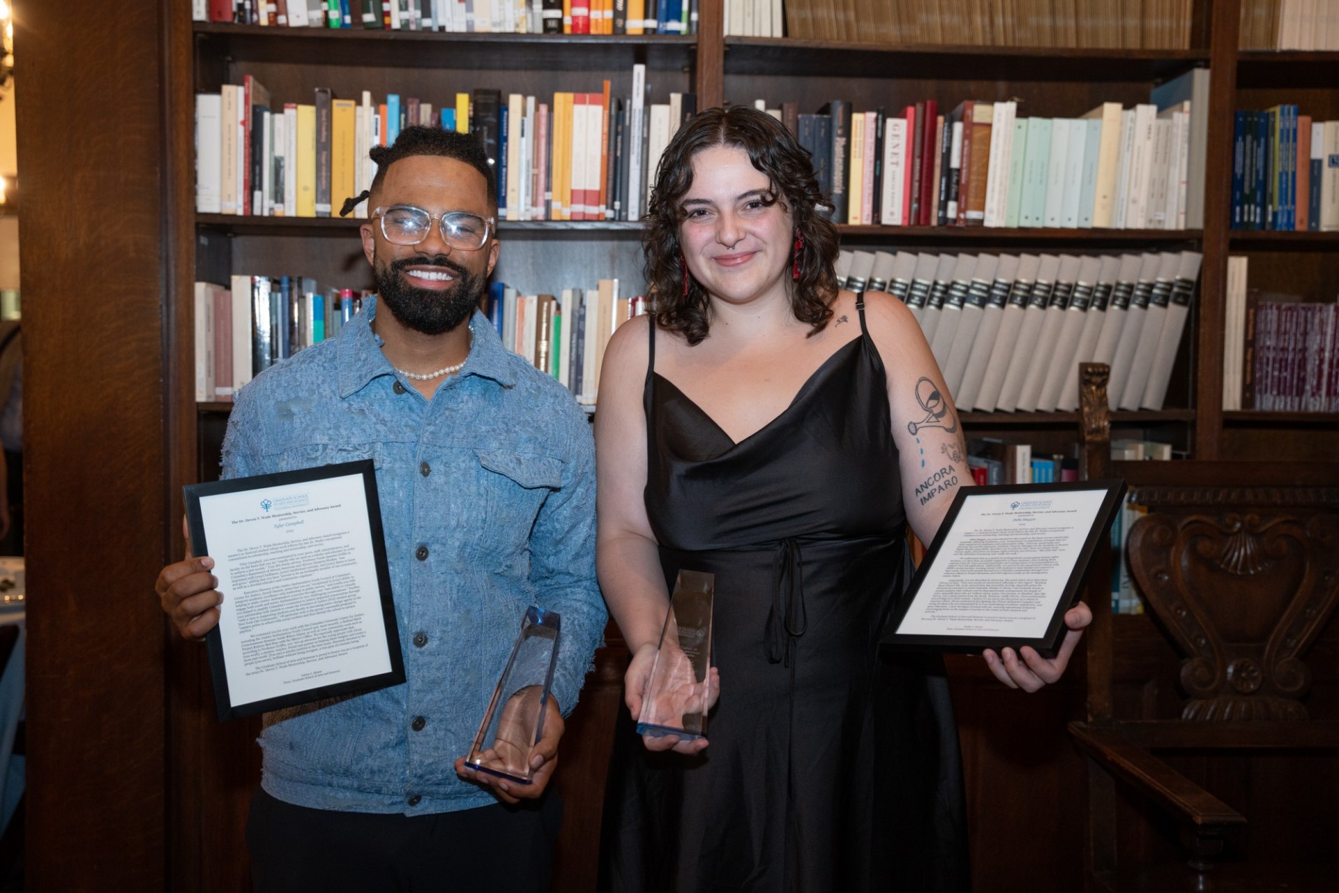 Man and woman holding up awards they won