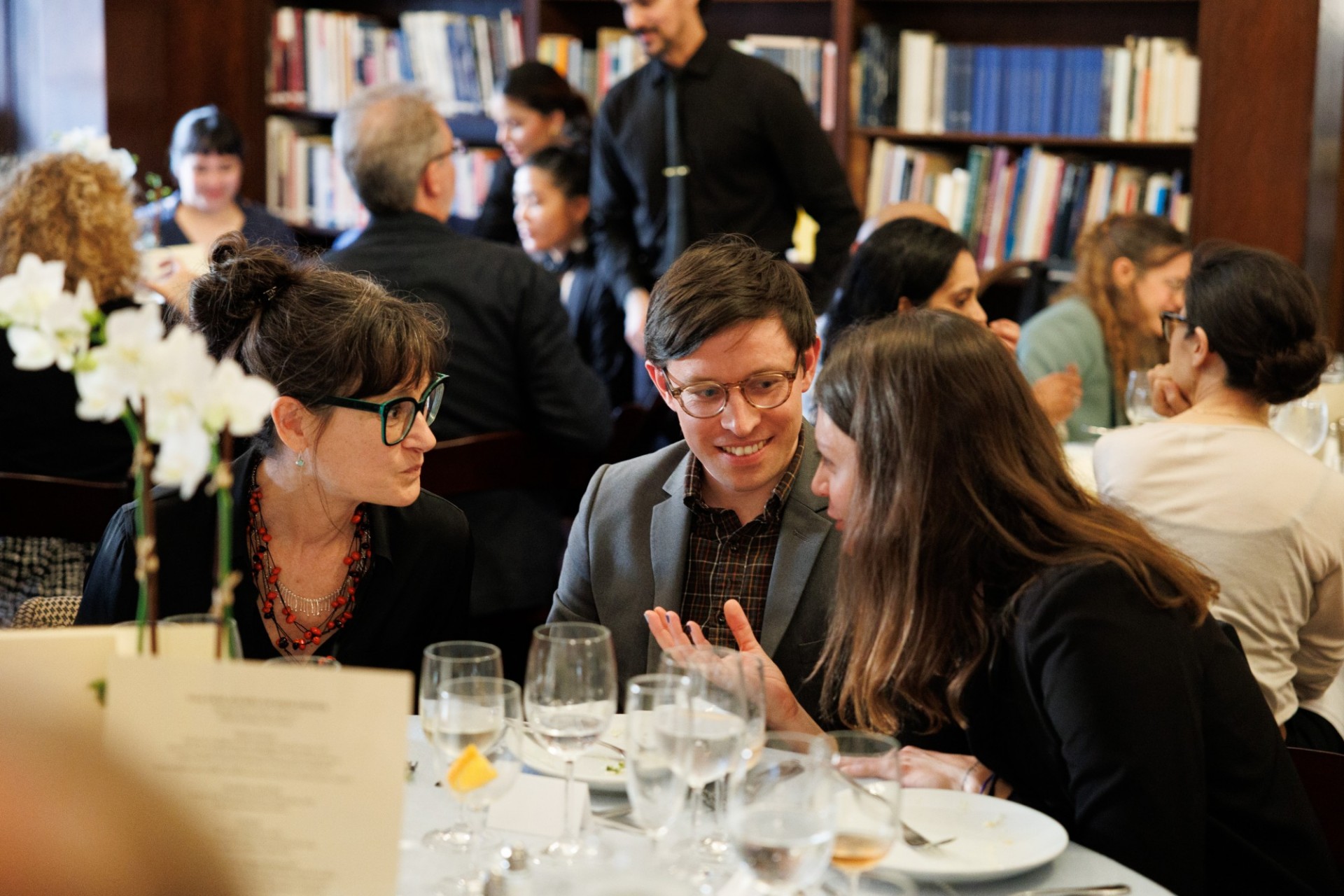 Faculty Mentoring Award winner, Nancy Worman (left) chatting with PhD student Brett Stine and alumna Emma Ianni. people talking seated at a dinner table