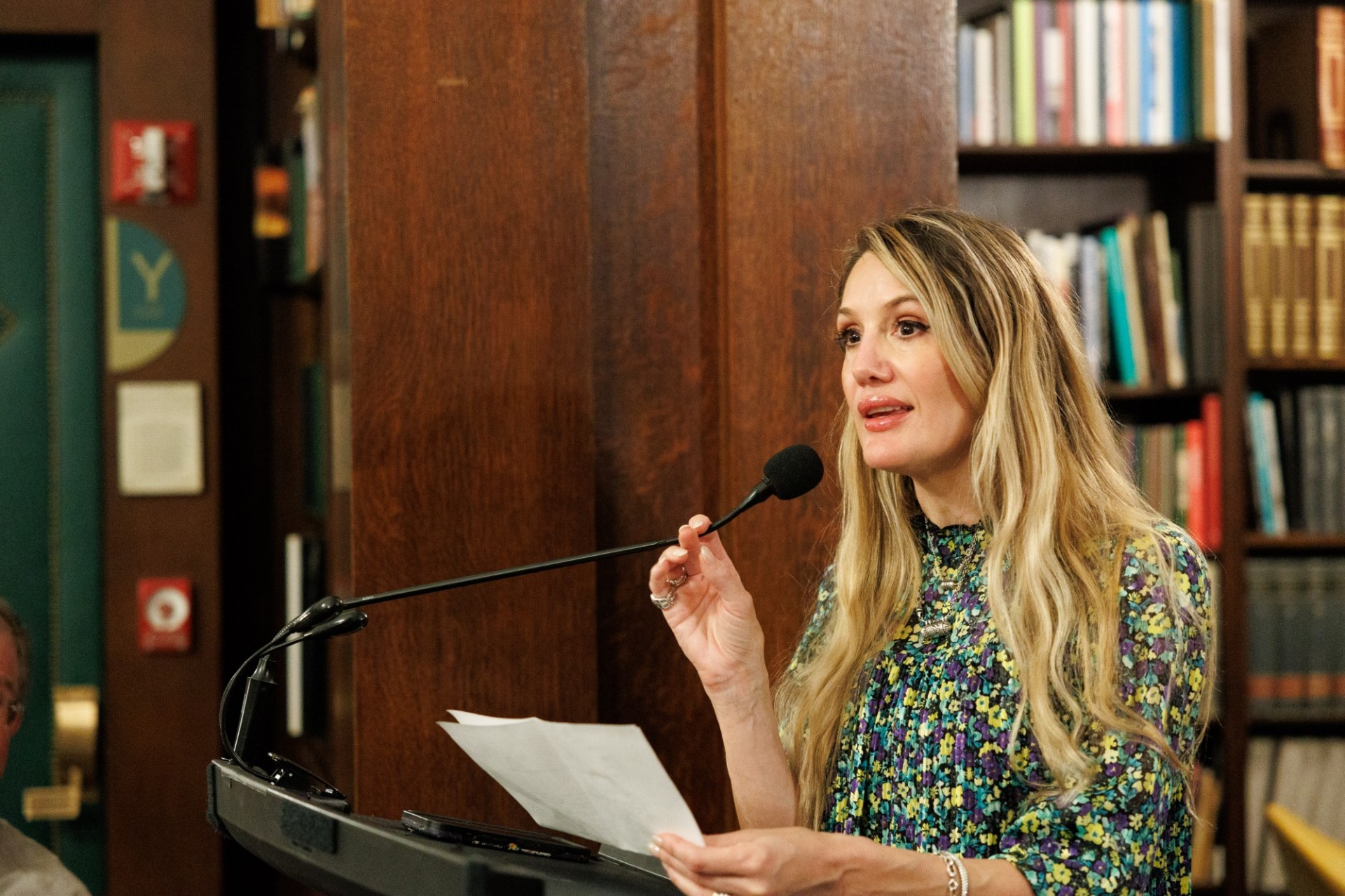 Kate Macdonald Falsini, accepting the Dean’s Award for Distinguished Achievement for her father, Timothy Macdonald. Woman with long hair at lectern speaking