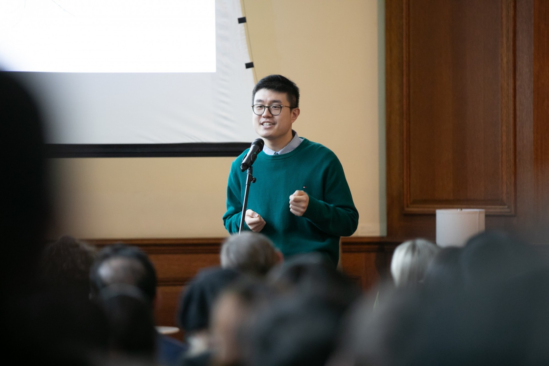 Male student giving a speech in front of a slide