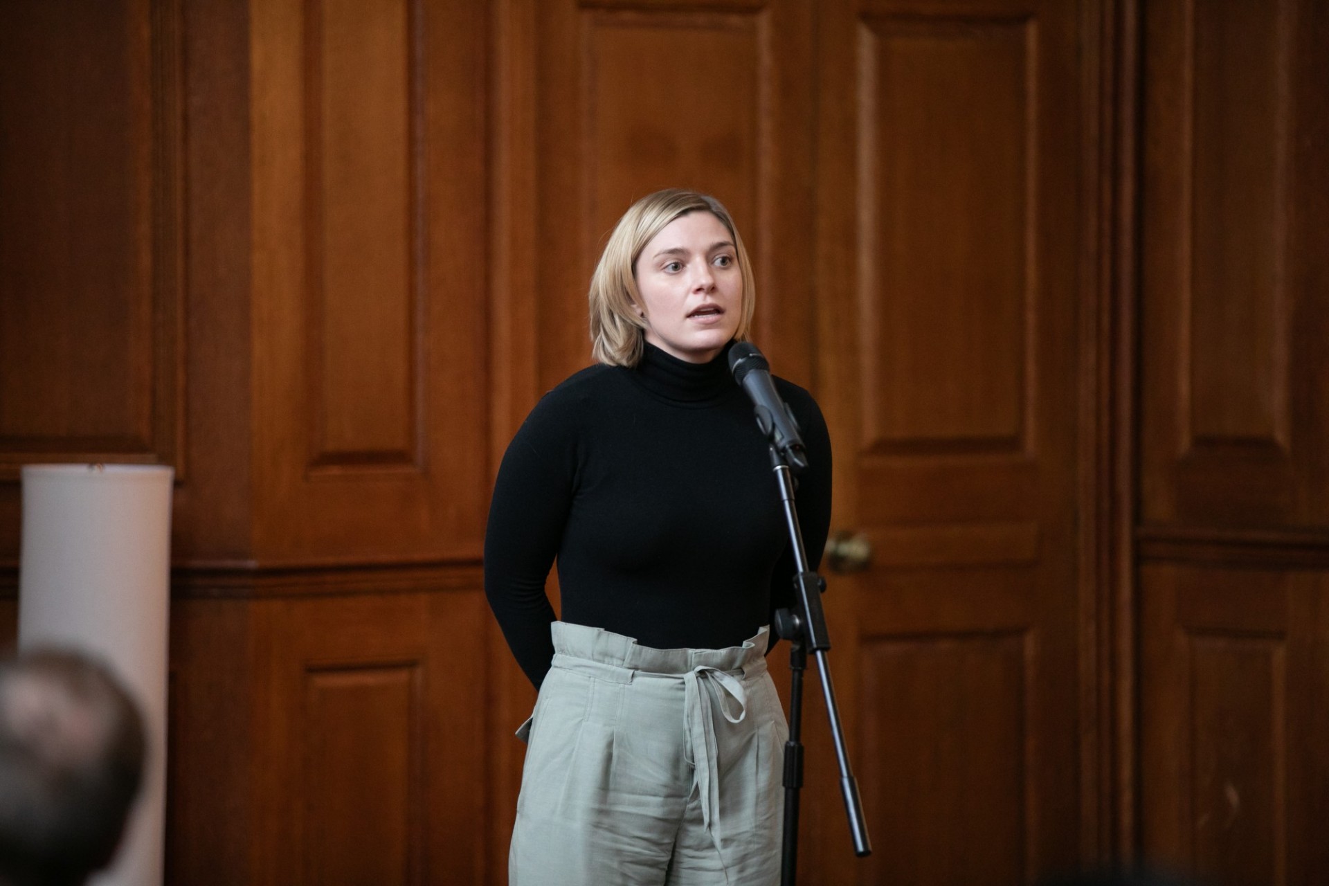Bonnie Siegler (GSAS) presenting Female student standing and giving a speech in front of a slide
