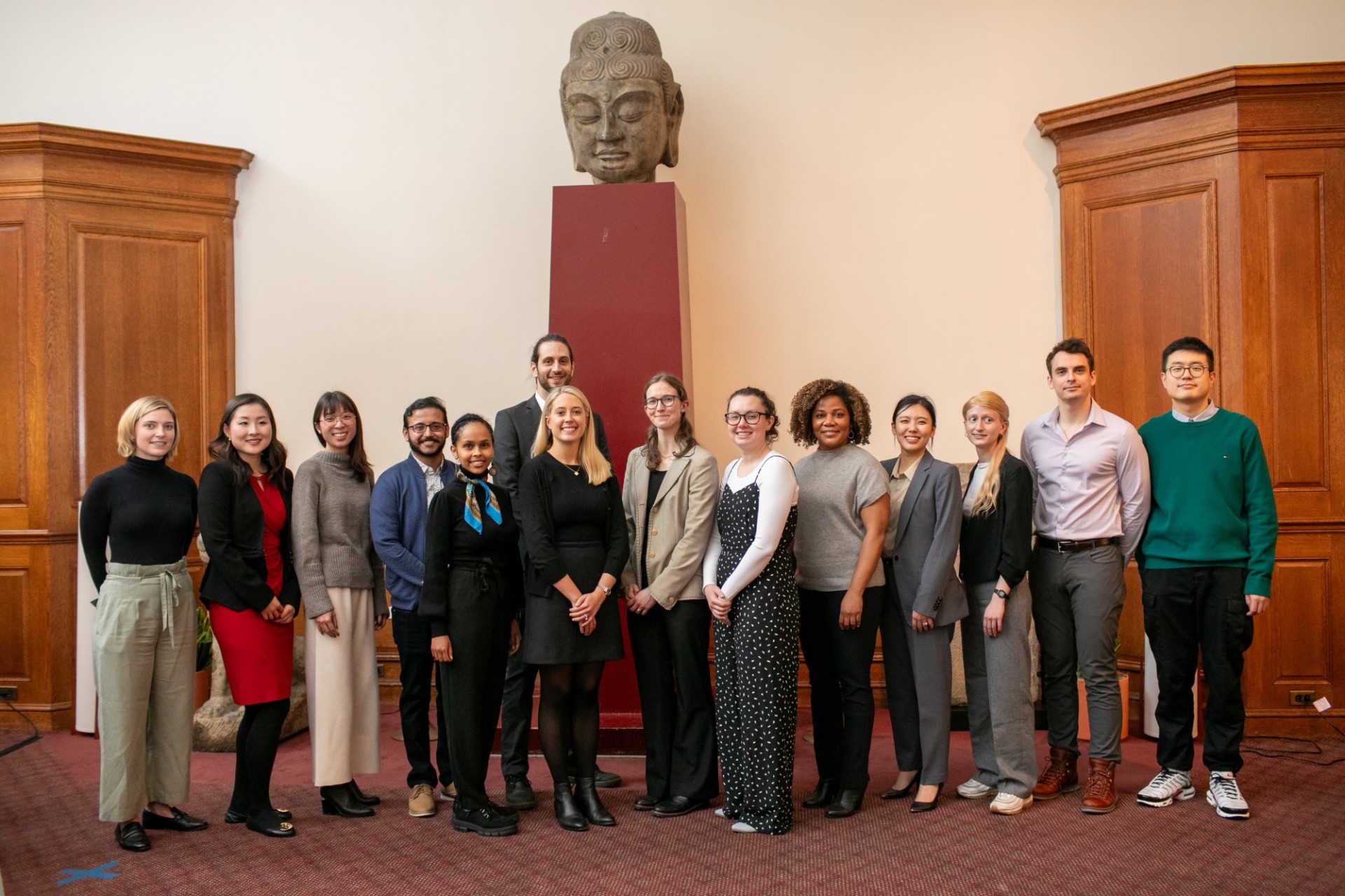 14 people standing in a row, smiling for camera