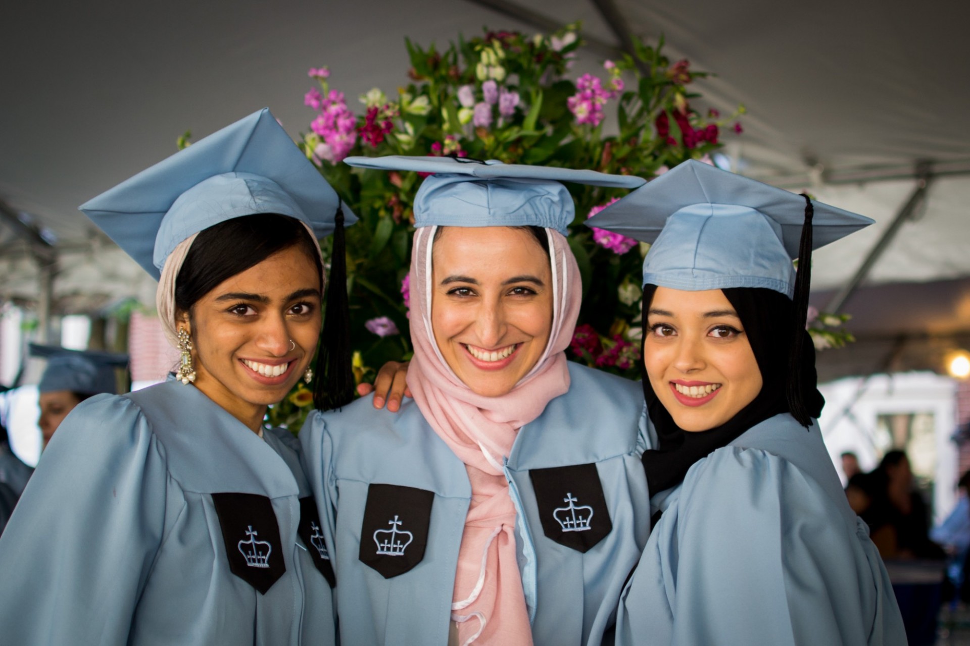 three students in cap and gown
