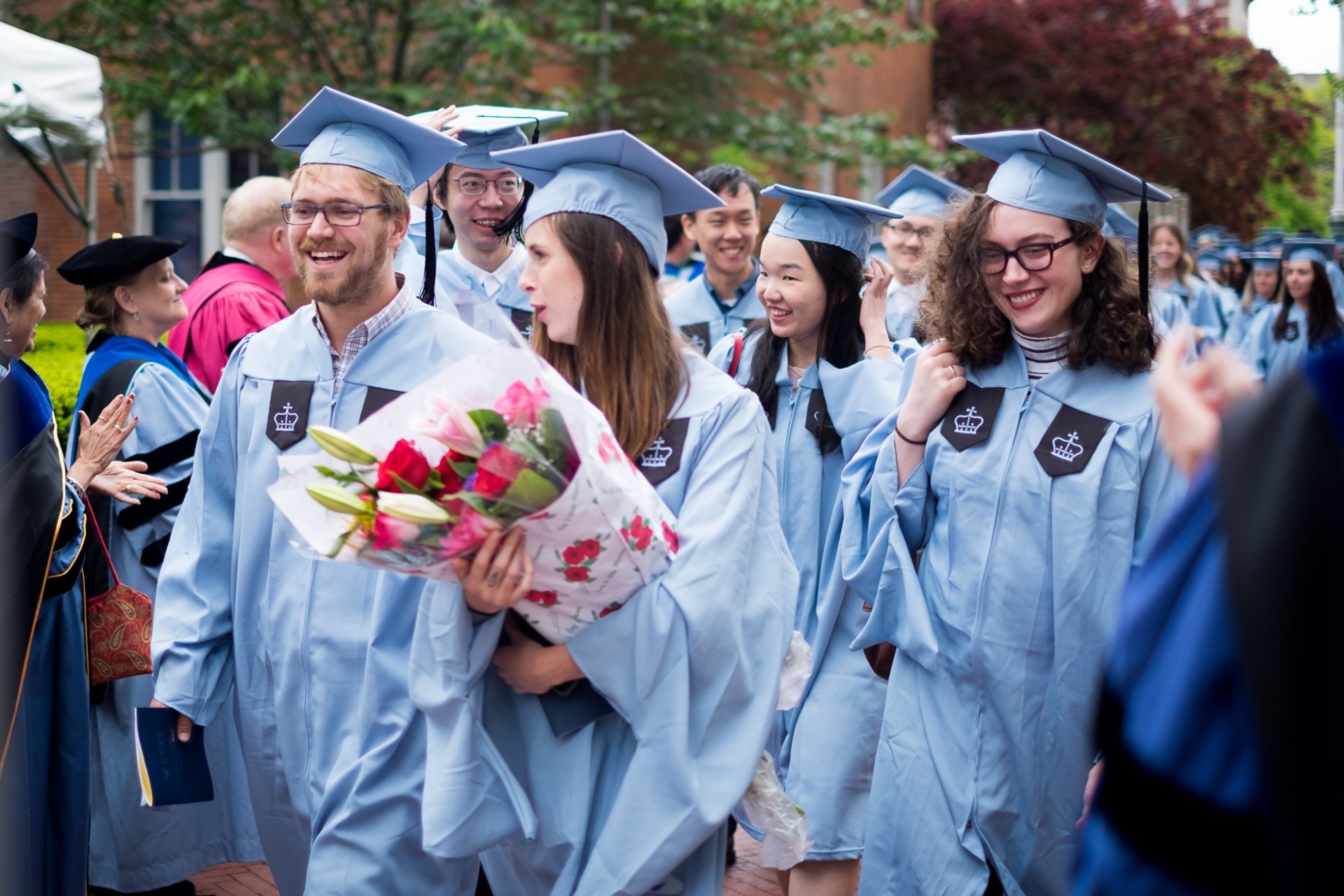 Beaming MA candidates make their way past applauding faculty following the ceremony.