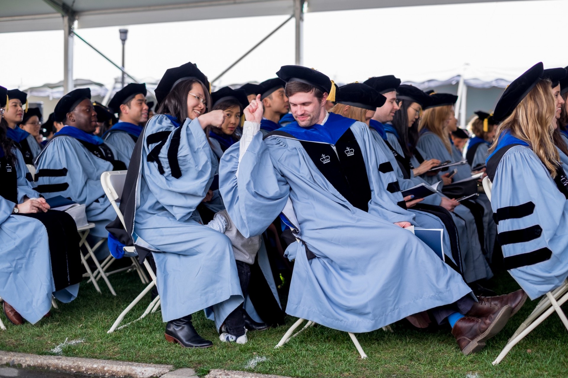 Two doctoral candidates share a fist-bump.