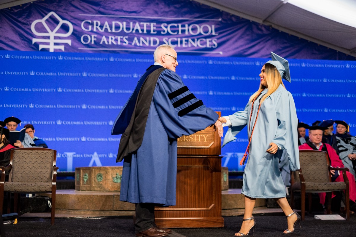 Dean Alonso greets Jacqueline Altamirano Marin, MA candidate in Human Rights Studies, as her name is read.