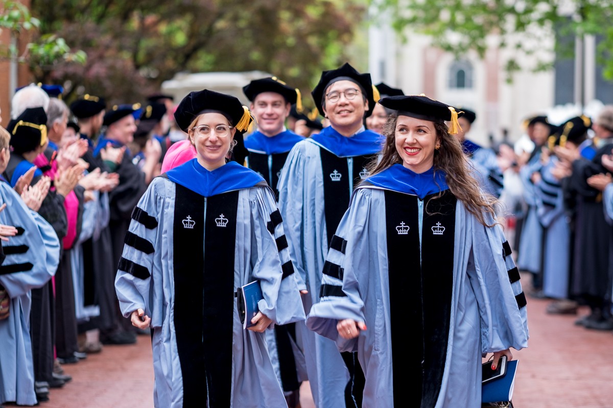 Faculty applaud the doctoral graduates as they leave the ceremony.