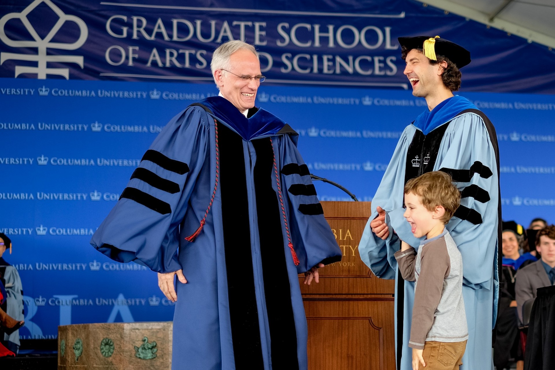 Dean Carlos J. Alonso, PhD, shares a laugh with a PhD candidate and his son.