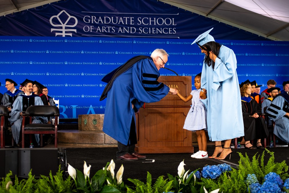 Dean Alonso greets an MA candidate and her daughter. Dean Alonso greets an MA candidate and her daughter.