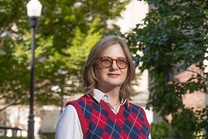 Woman with light brown shoulder length hair and glasses smiling to camera