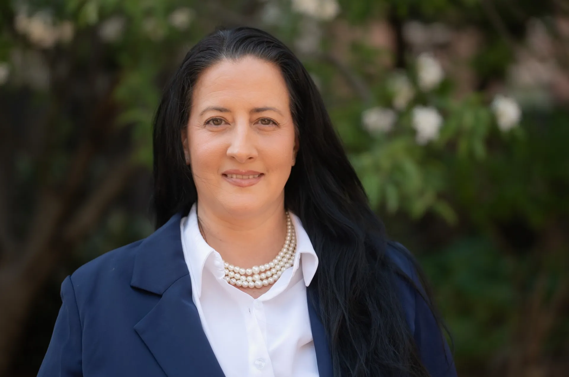 A portrait of a woman with long brown hair wearing a blazer. 