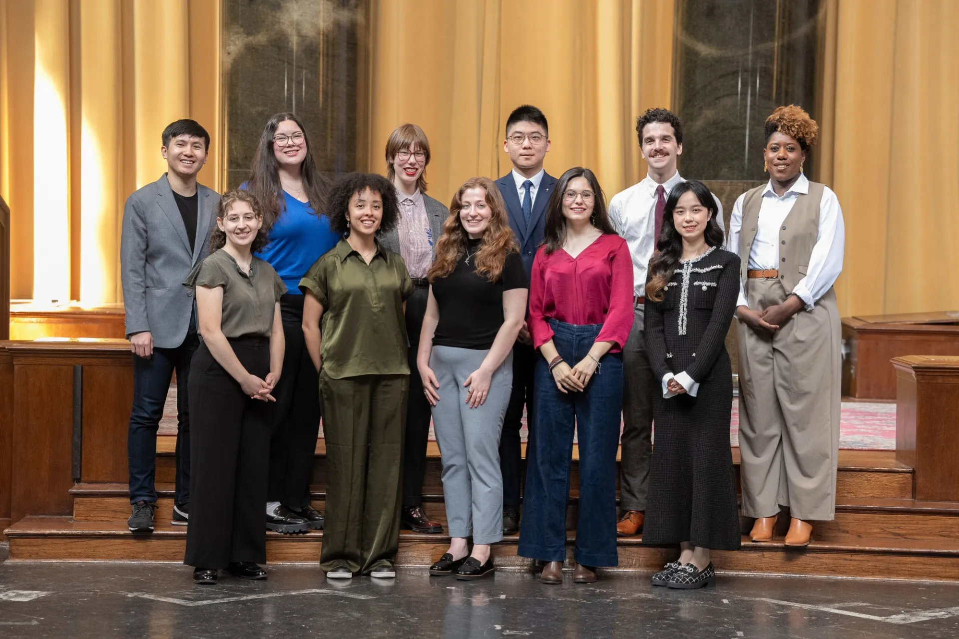Twelve students smiling in a group photograph. 