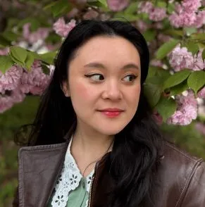 A headshot of a woman standing in front of a flowering tree. 
