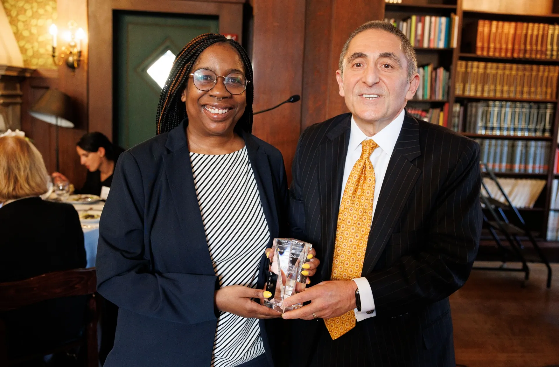 Two people smiling and holding a crystal award. 