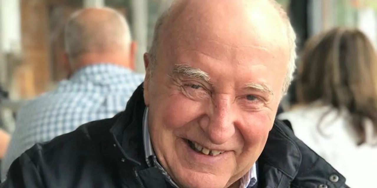 An elderly man smiles for a photo.