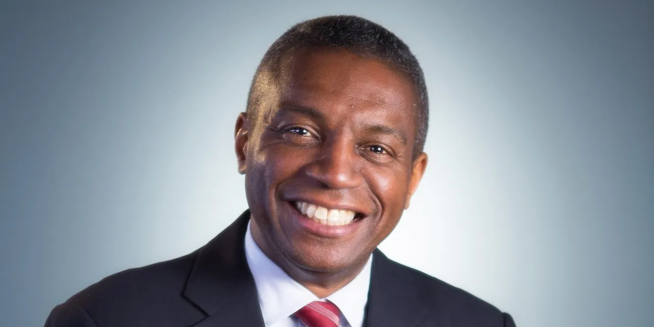A smiling portrait of a man in a business suit.