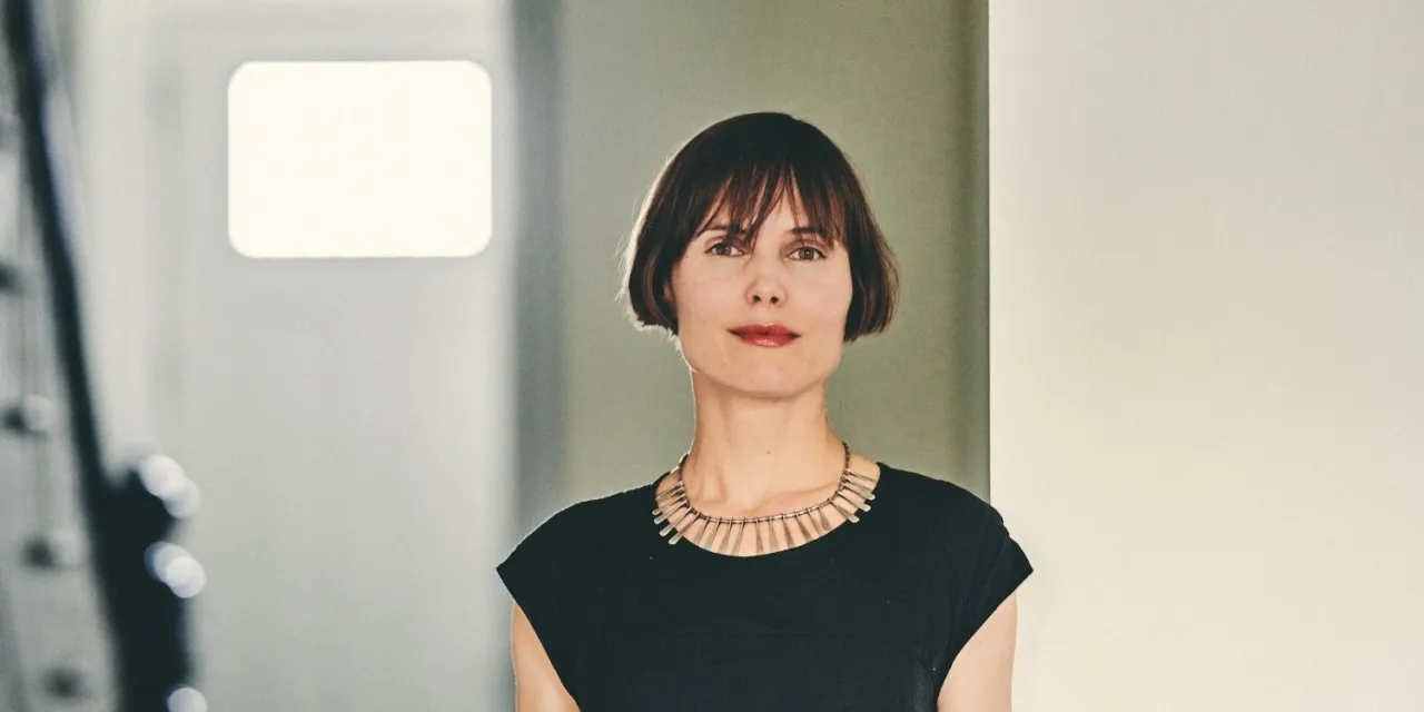 A portrait of a woman with bangs, a short bob, wearing red lipstick.