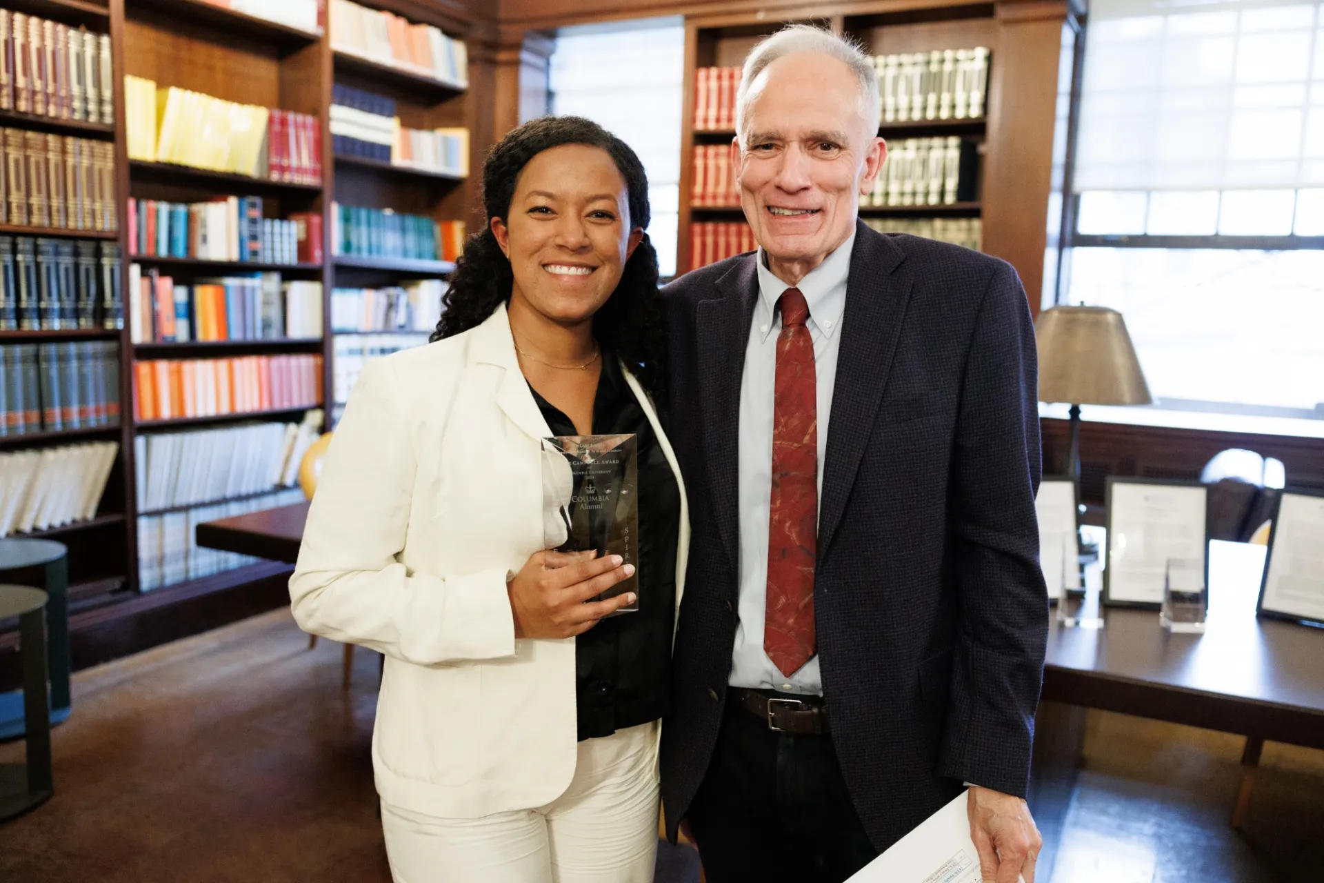 Woman holding award standing next to older man