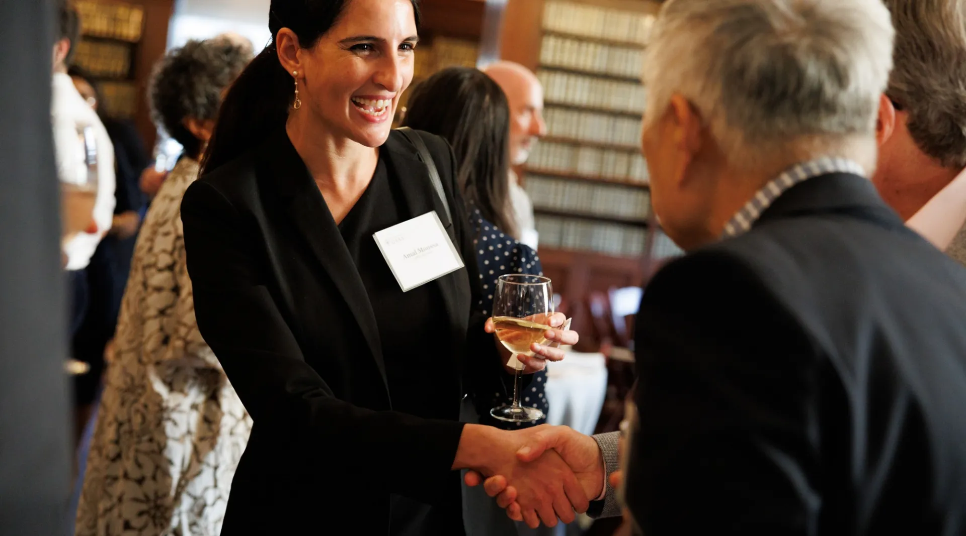 A woman in a suit shaking hands with someone.