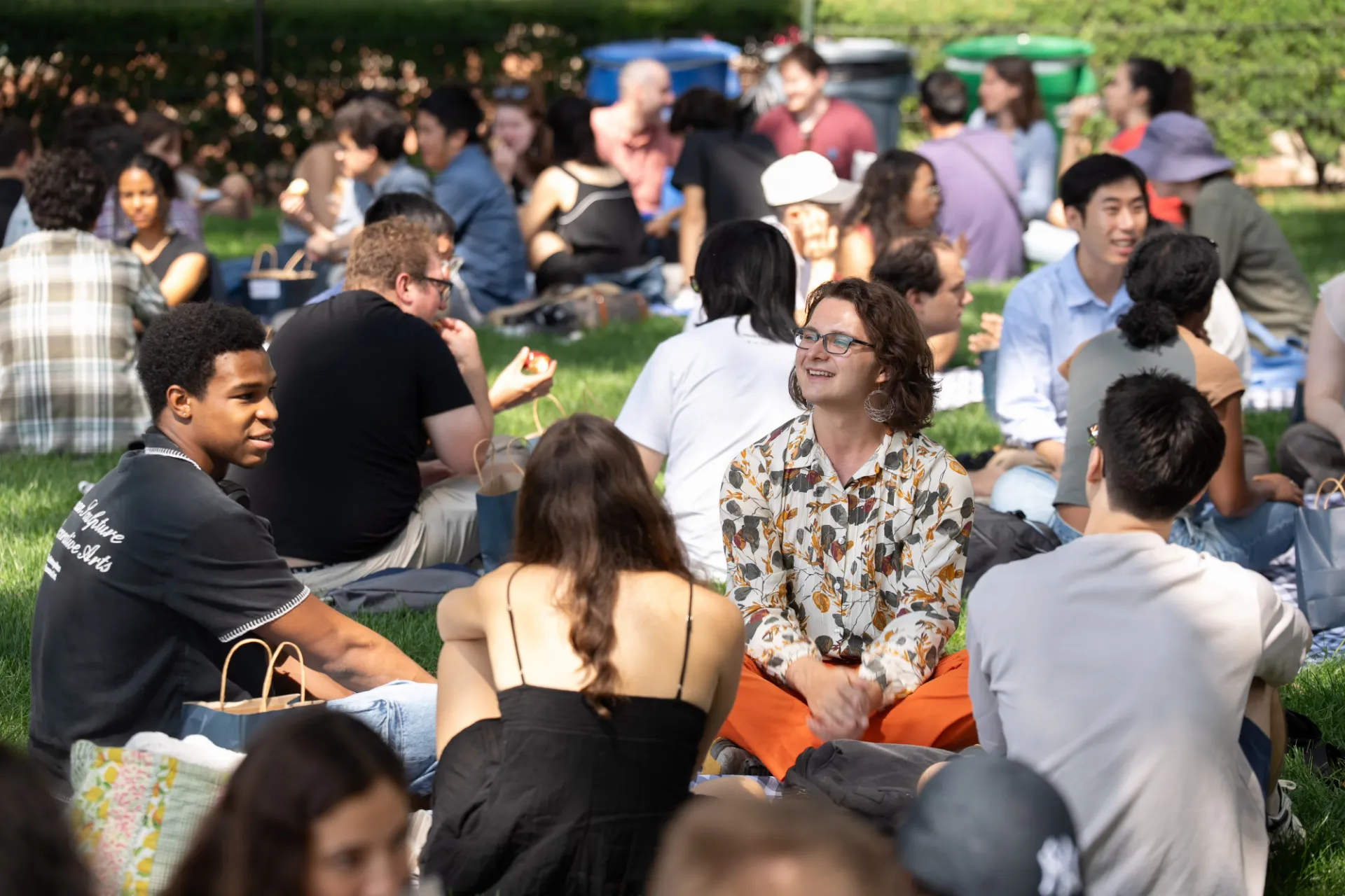 Students having a picnic on the grass, smiling.