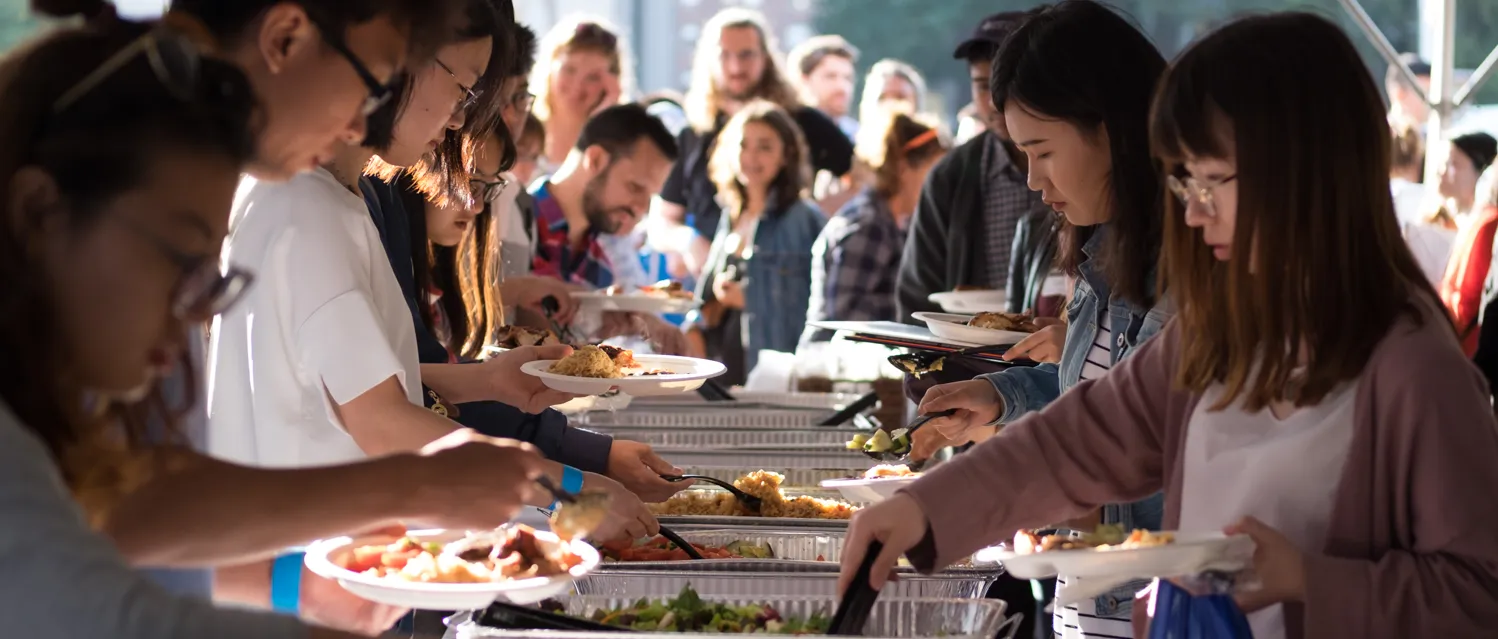 Students helping themselves to food at a buffet event.