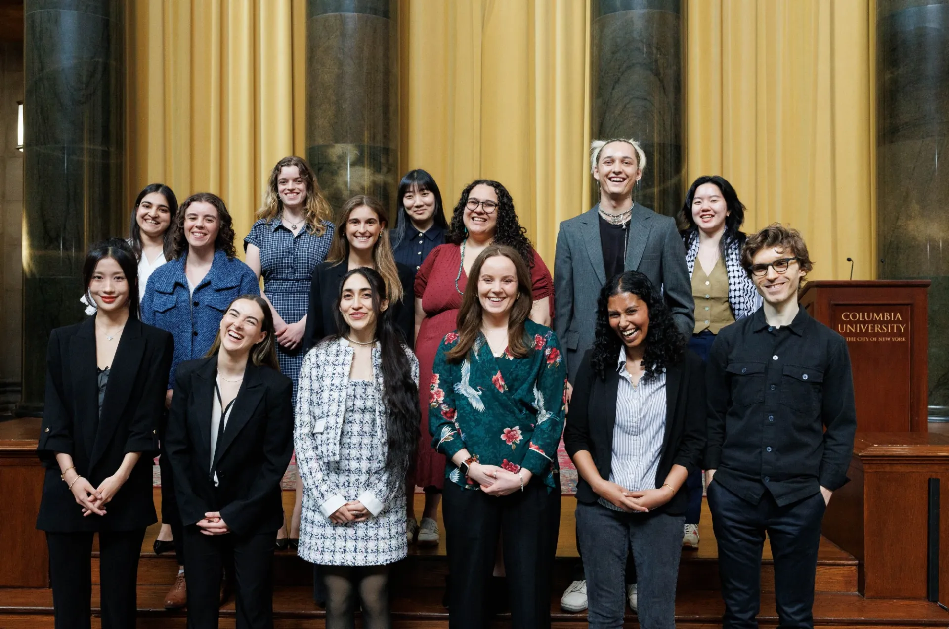 group of students in 3 rows standing and smiling to camera