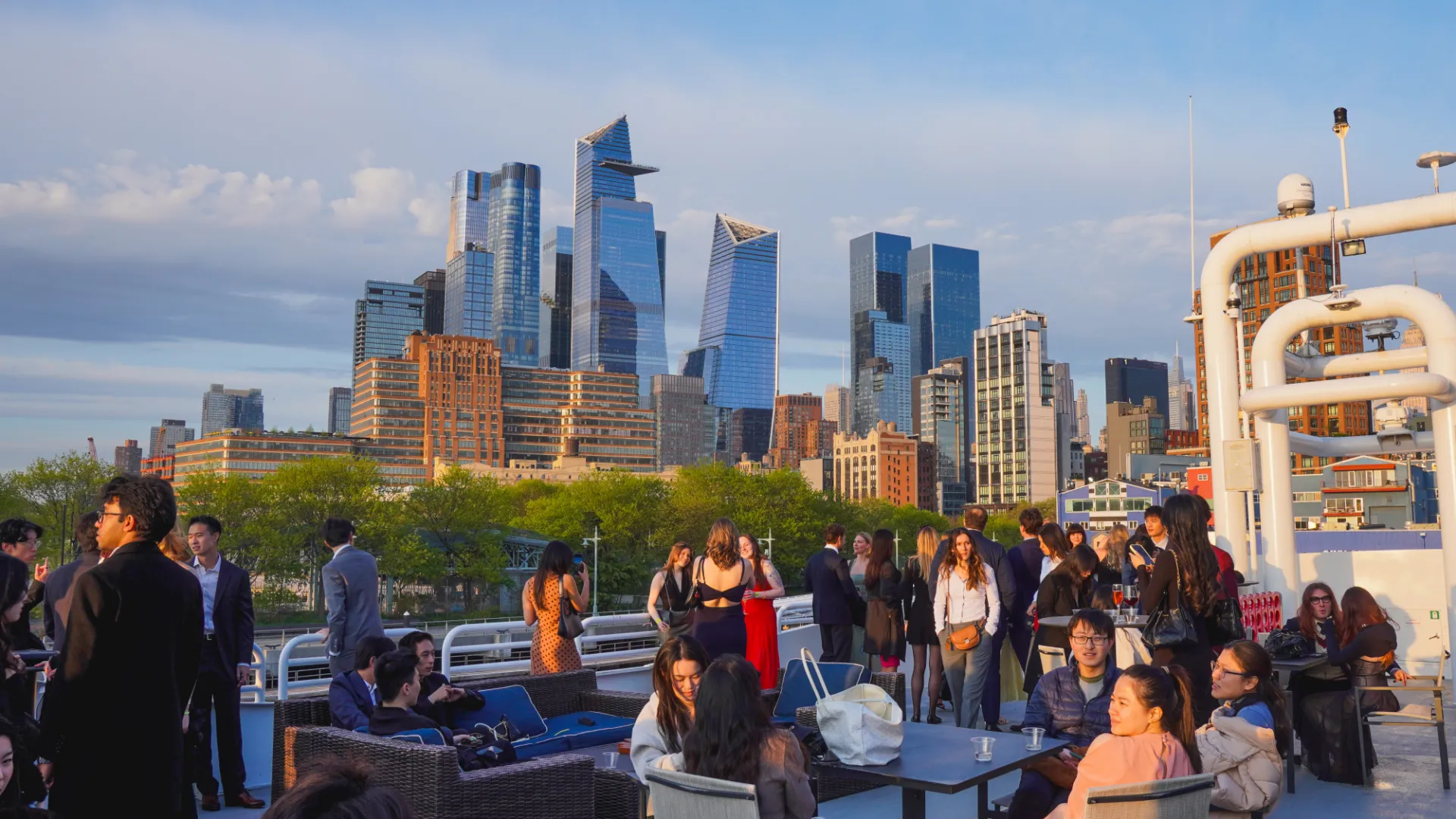 Students mingle on a boat with lower Manhattan in the background
