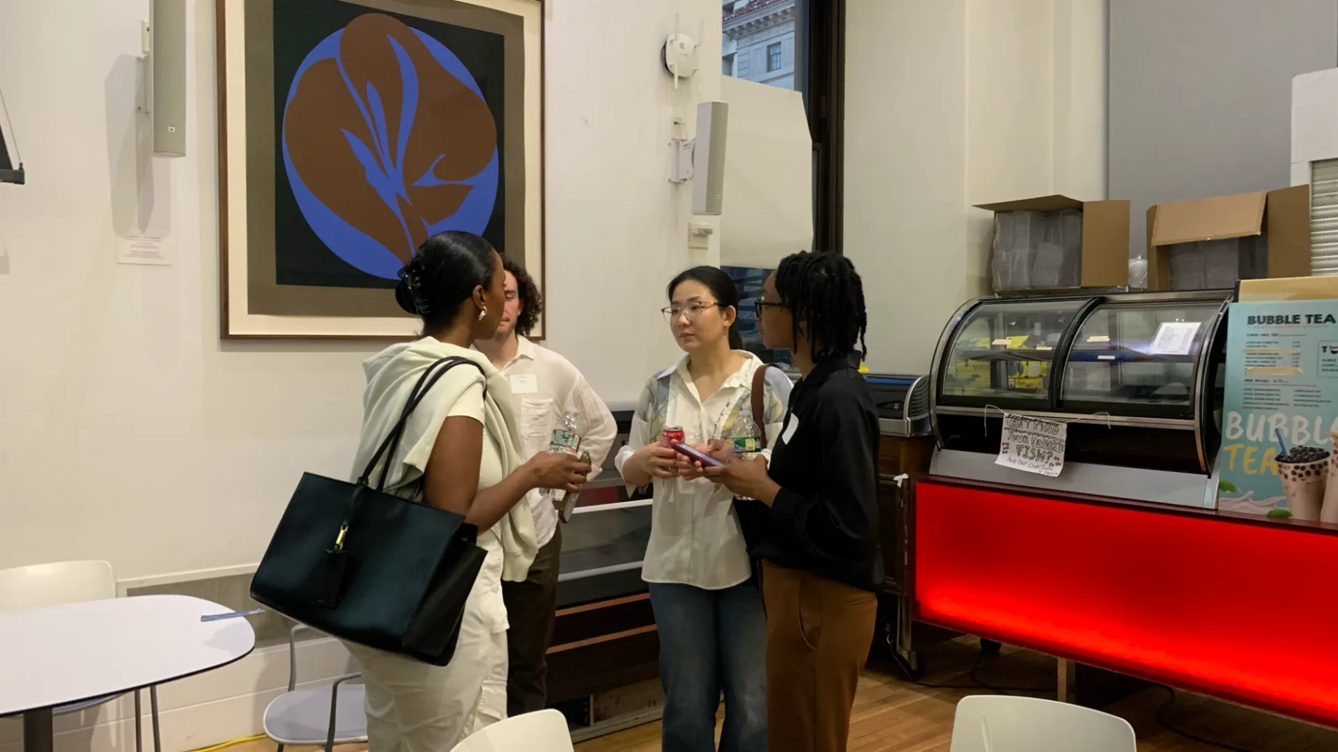 A group of students holding drinks talk in a circle at a coffee shop.