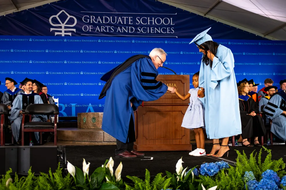 Dean Alonso greets an MA candidate and her daughter.