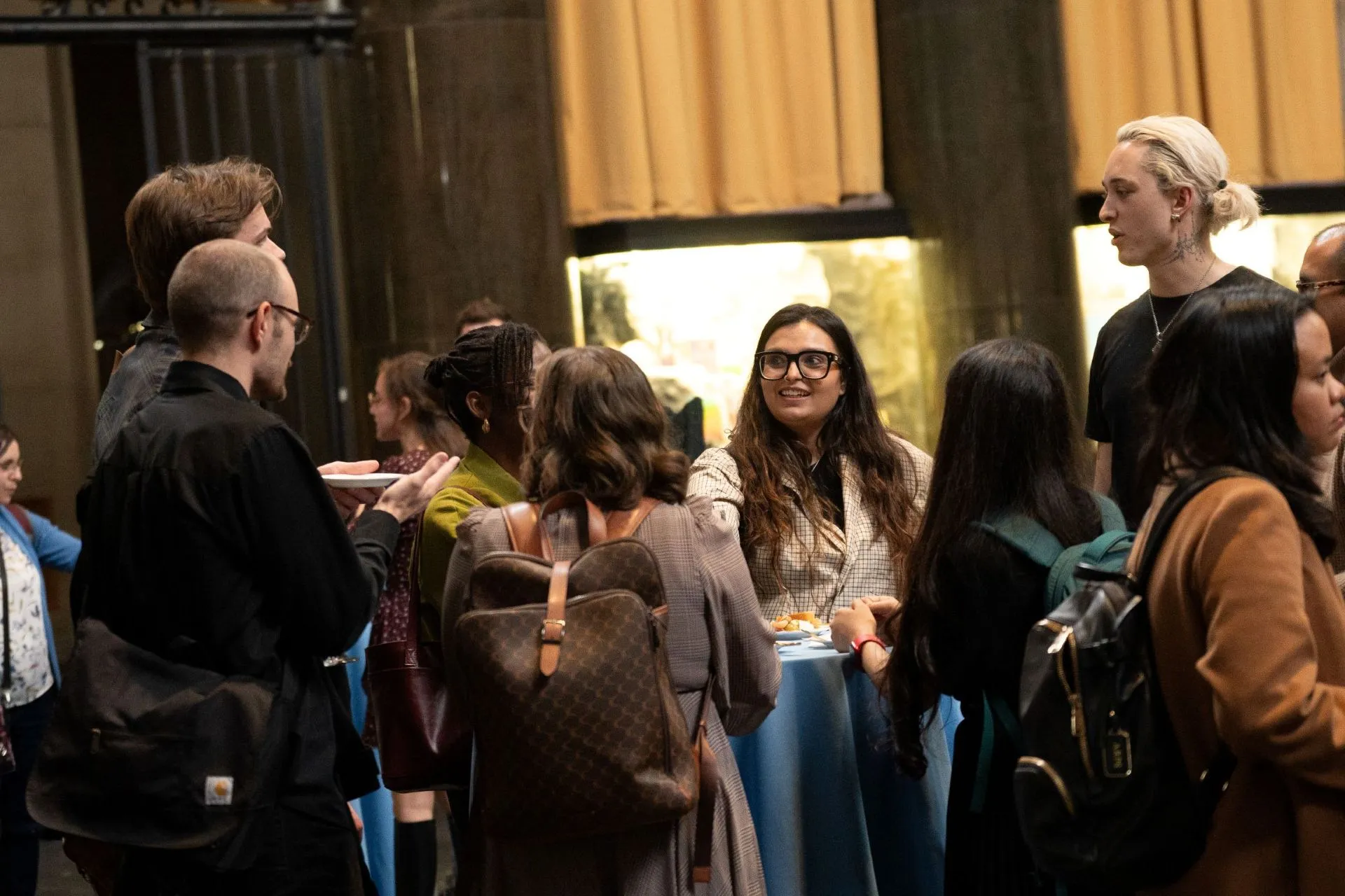 Students and attendees smile and talk and eat food at the reception.
