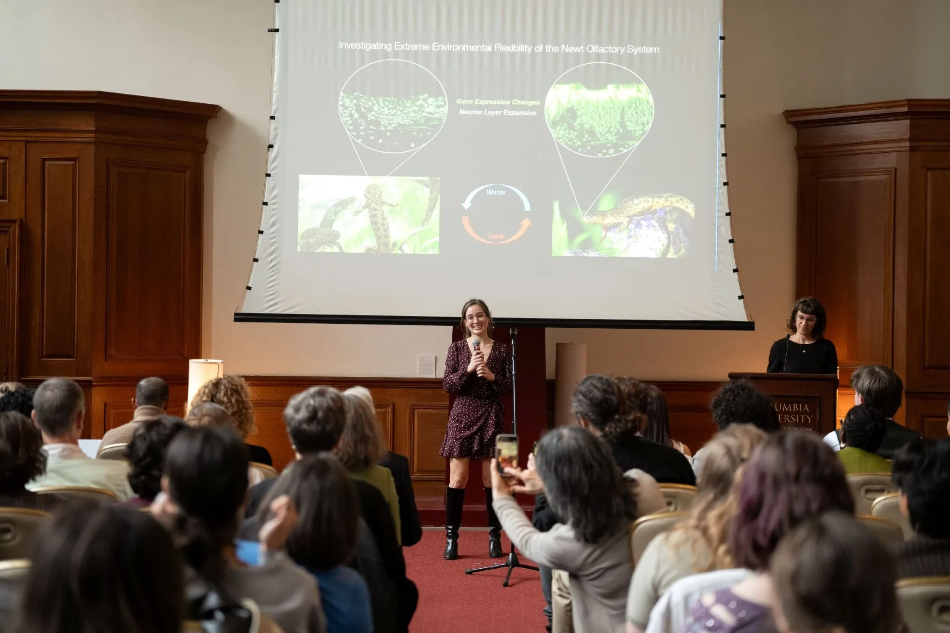A woman presents on newts before an audience.