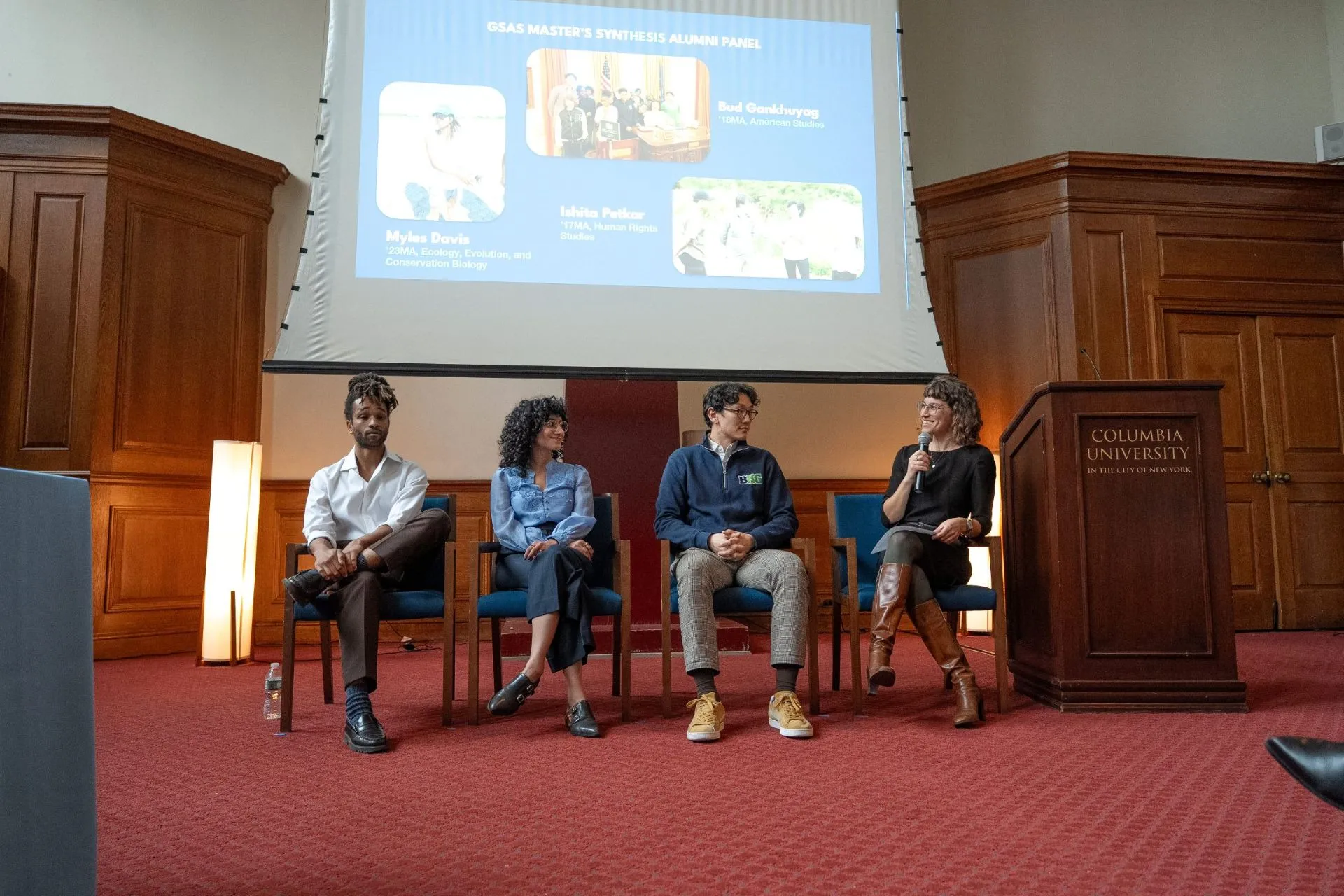 A group of speakers sit in chairs and engage in panel discussion.